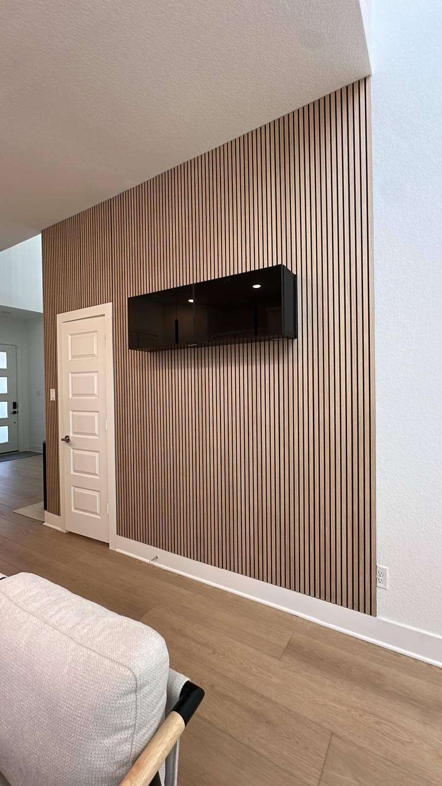Modern interior featuring a vertical wood slat wall and a floating black glossy cabinet.